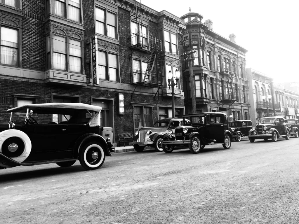 IMG_4912 A black and white photo of old cars parked in front of a building.